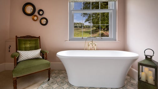 The freestanding bath under the window with a green velvet chair next to it, in the second-floor main bedroom at Blckling Tower in Norfolk